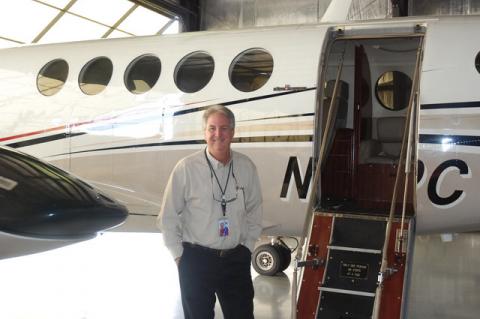 Air Unlimited co-founder and pilot Mark Neubauer stands next to a twin prop plane that is part of the airline’s fleet.