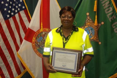At the Seminole County Sheriff’s Office, Star Myers holds up her plaque naming her the Crossing Guard of the Year for 2019 for the State of Florida.