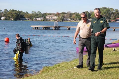 Dive team commander Lt. Paul Pratt, tan shirt, walks with Sheriff Dennis Lemma on the shores of Bear Lake as divers get ready for the demonstration of a new underwater, remote-controlled drone.