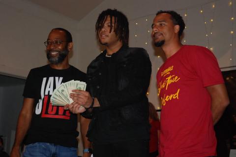 Florida Boi JJ shows off his cash prize Thursday as Showtime in Sanford host Jay Love, left, and organizer Laurence Gordon, right, look on.