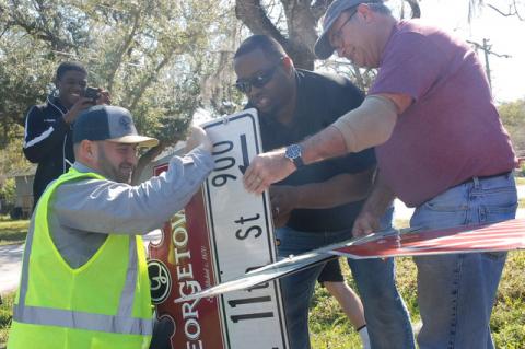 Sanford Mayor Art Woodruff, right, and Commissioner Kerry Wiggins Sr. work on the sign topper at Willow Avenue and 11th Street with Sign Tech Tom Puleo, left.