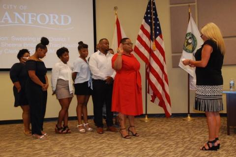 City Clerk Traci Houchin (right) swears-in District 1 Commissioner Sheena Britton (center) with her family behind her. 