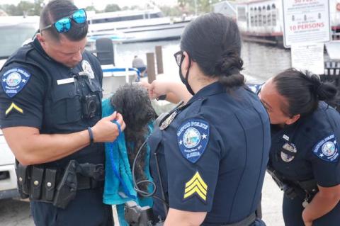 Officer Hernandez (left) holds the puppy that he helped rescue from Lake Monroe. He later adopted the dog, Moonie. 