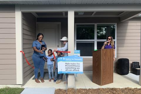 Tori Hutto (left) cuts the ribbon on her new home with her twins and Habitat for Humanity Seminole-Apopka CEO Penny Seater.