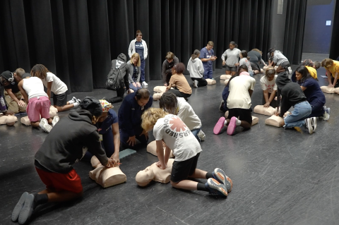 Students at Lyman High School practice CPR on dummies while members of the Advent team instruct them.