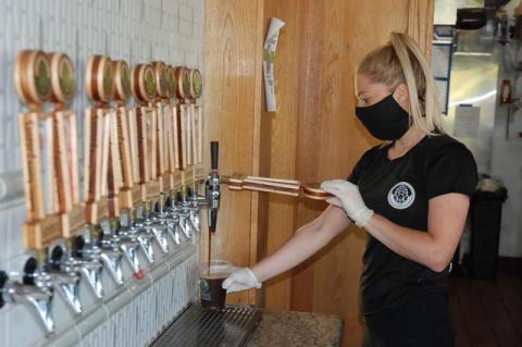 Sanford Brewing Company employee Taylor Liebelt pours beer for their first seated customers on Monday. 