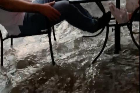 Screencapture from Facebook video in the Breezeway on the north side of 1st Street, where flood water flowed under the seats of customers.